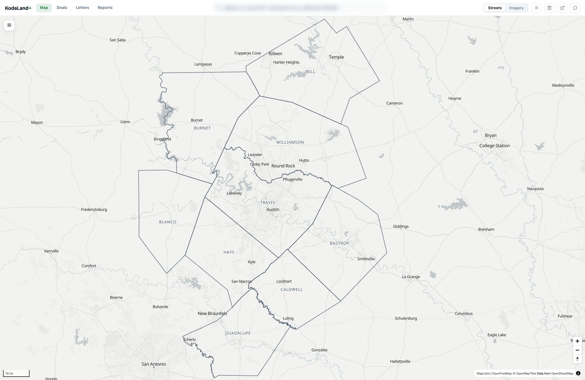 The KodaLand map zoomed all the way out to the whole nine-county Austin metro on the streets basemap, with the county boundaries drawn as clear slate lines and each county labeled: Bell, Burnet, Williamson, Travis, Blanco, Hays, Caldwell, Bastrop and Guadalupe. City labels sit throughout the metro (Georgetown, Round Rock, Austin, Leander, San Marcos, Killeen, Temple, New Braunfels), and the app's search bar reads 'Address, or county:PID / county:geo-ID'.