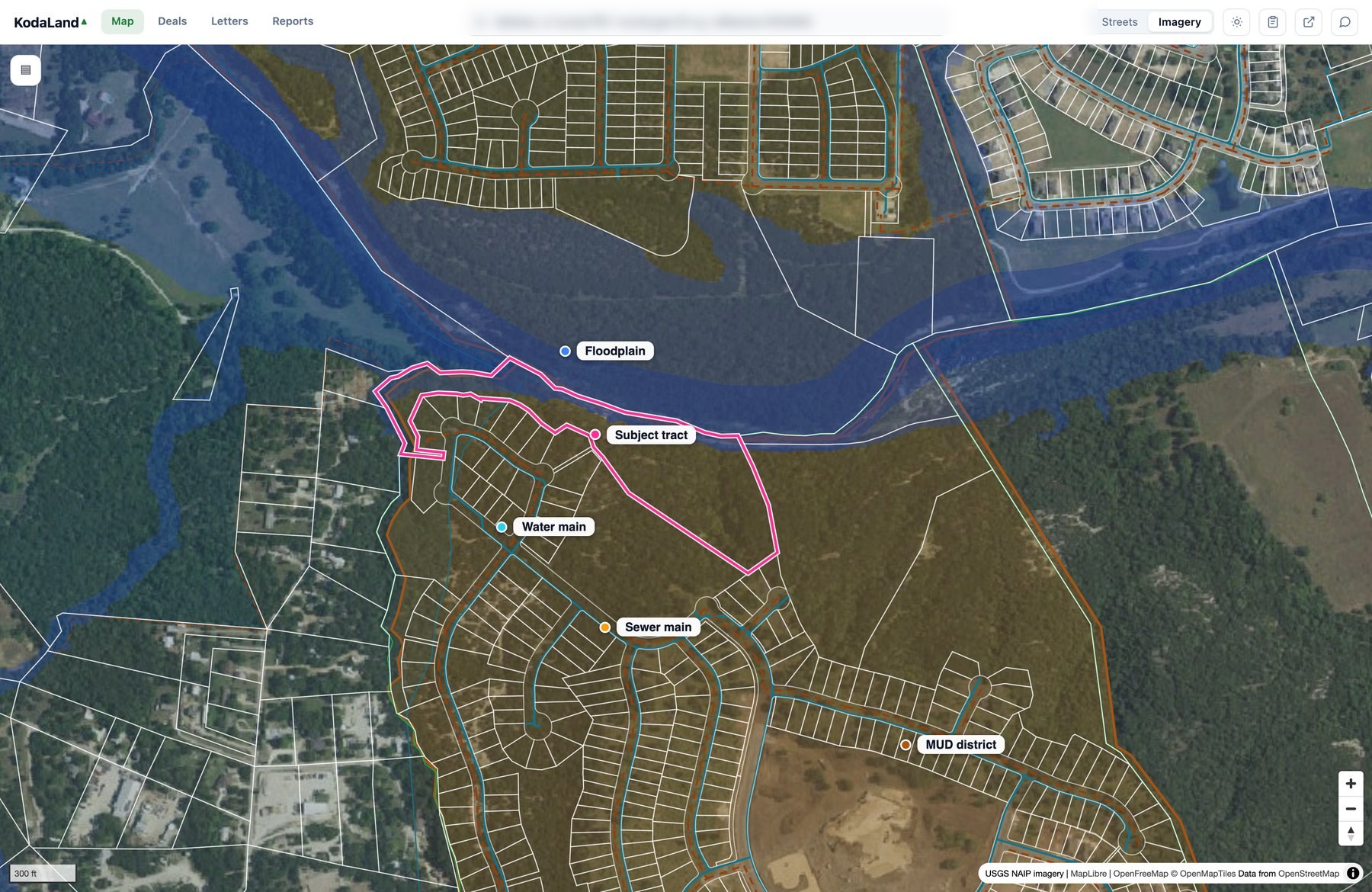 A screen of the KodaLand app over a Leander tract on aerial imagery: white property lines fill the view, the FEMA floodplain washes blue along the South Fork San Gabriel River, cyan water mains and orange sewer mains run through the neighborhood streets, and a Municipal Utility District is drawn as an amber-tinted service area with a bold boundary. The subject tract is outlined in magenta, and labeled markers name the floodplain, a water main, a sewer main, the MUD district, and the subject tract.